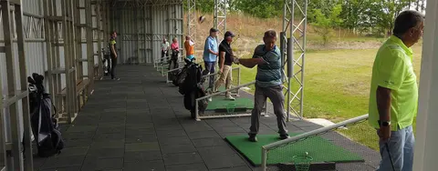 Golfer trainieren an den überdachten Abschlagplätzen der Driving Range