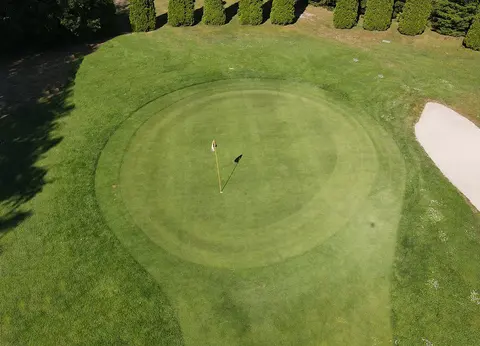 Rundes Grün mit Fahne und angrenzendem Bunker von oben gesehen