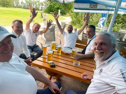 Gut gelaunte Golfer stoßen nach der Runde auf der Terrasse des Clubhauses in Mahlow an