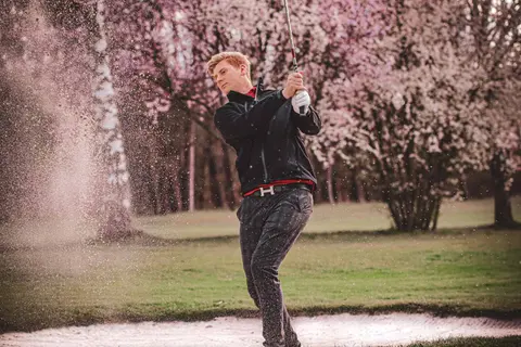 PGA Professional Richard Verpeléti spielt einen Bunkerschlag, der Sand spritzt auf