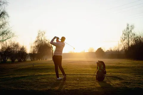 Golfer im Abschwung auf dem Fairway bei tief stehender Abendsonne