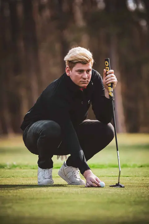 Golflehrer kniet auf dem Grün und liest die Puttlinie